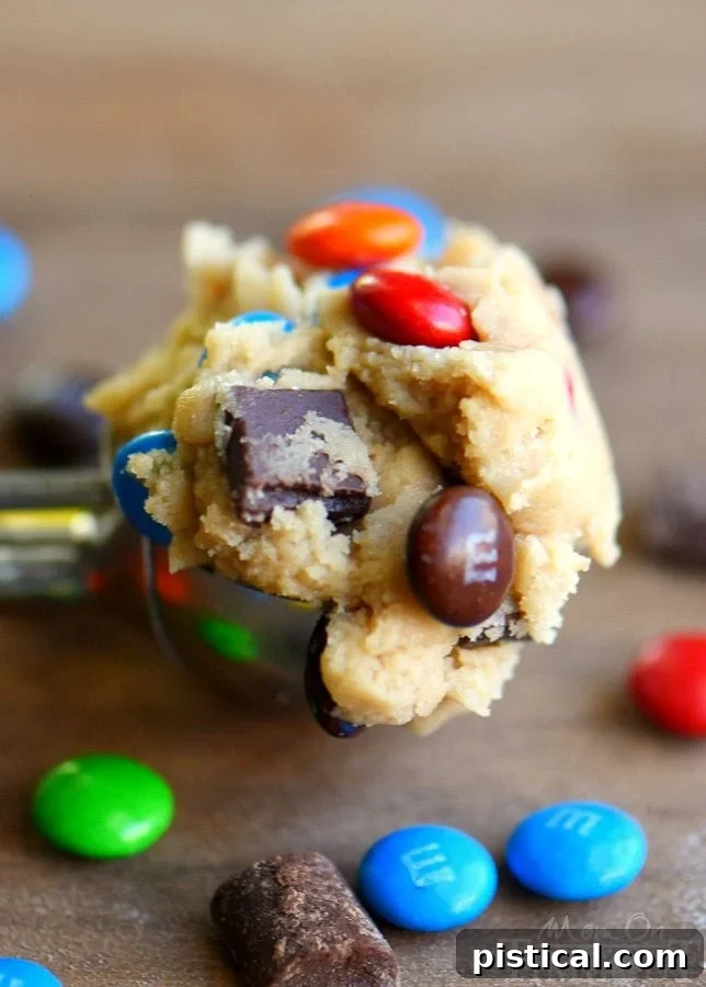 Hand holding a freshly baked M&M and chocolate chunk cookie, showing its inviting texture.
