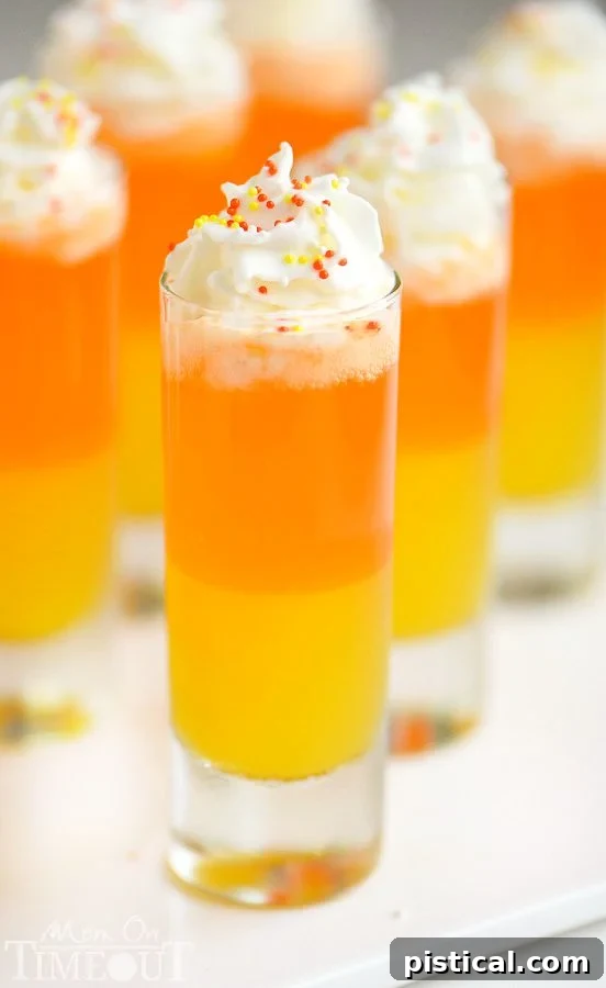 Candy Corn Nibbles 5 Two hands holding Candy Corn Poppers, highlighting the beautiful layered effect and the fun, kid-friendly nature of the drink.