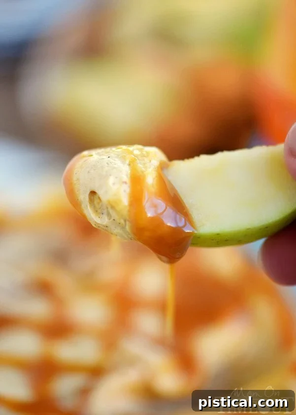 Assortment of dippers, including sliced apples, graham crackers, and vanilla wafers, around a bowl of Caramel Pumpkin Cheesecake Dip