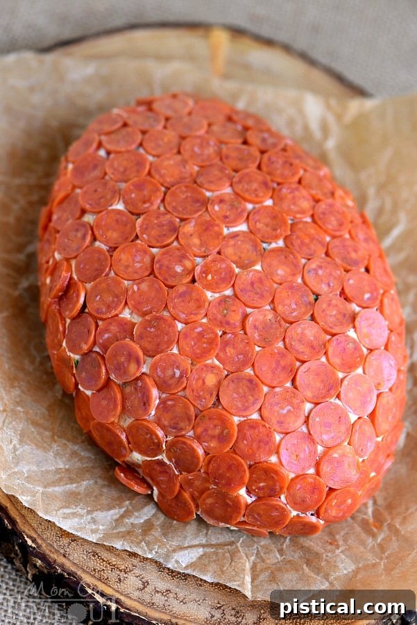 The blended cheese ball mixture, shaped into a football and wrapped in plastic, ready for chilling.
