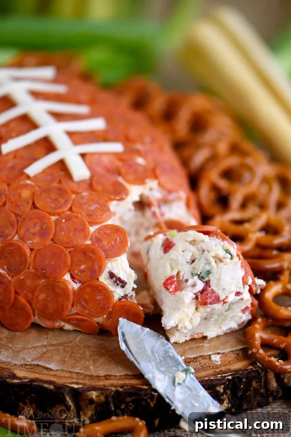 A vibrant platter featuring the Pepperoni Pizza Football Cheese Ball surrounded by various dippers, perfect for sharing.