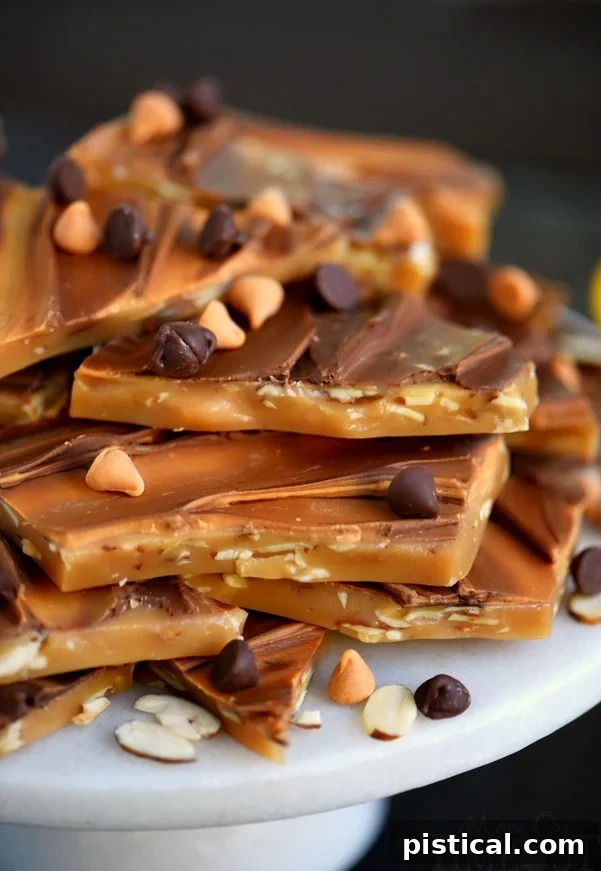 A tall stack of freshly made almond toffee pieces arranged on an elegant cake plate, ready for serving