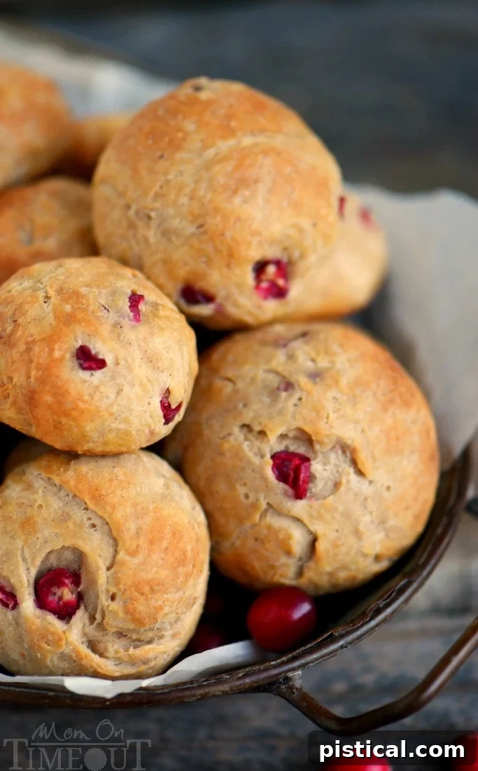 Close-up of golden-brown yeast rolls with fresh cranberries, highlighting their festive appearance.
