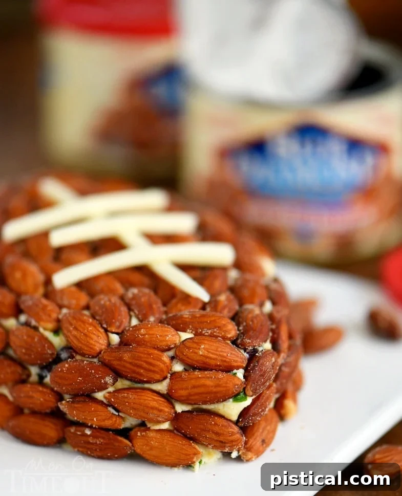 A Cranberry Almond Cheese Ball shaped like a football, perfect for game day or holiday parties, with a sprinkle of green onions and cranberries.