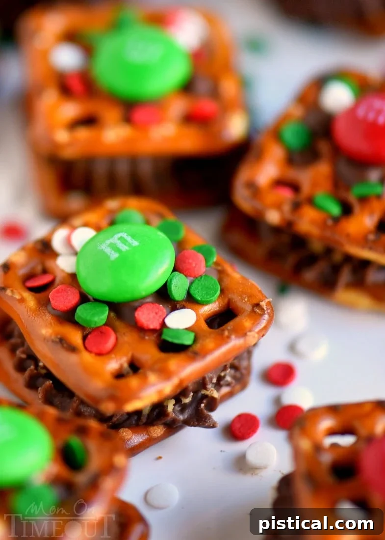 Reese's Festive Sweet and Salty Pretzel Treasures 4 A hand gently pressing an M&M onto a softened Reese's Peanut Butter Cup on a pretzel bite.