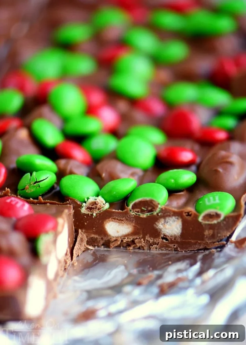 Freshly made M&M's Marshmallow Dream Bars chilling in a lined baking dish, ready to set before cutting.