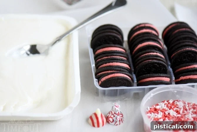 Learn the easy steps to dipping perfect Holiday Dipped Oreos! My how-to instructions and tips guarantee gourmet results in no time, making festive gifting simple. // Mom On Timeout #holidays #christmas #oreos #dippedoreos #candy #cookies #cookietray #dessert #easy A hand dipping a Peppermint Oreo into a bowl of melted white candy coating using a specialized three-pronged dipping tool, demonstrating the precise technique.