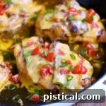 Four servings of Monterey Chicken still in the skillet with diced tomatoes and green onions scattered on top for garnish.