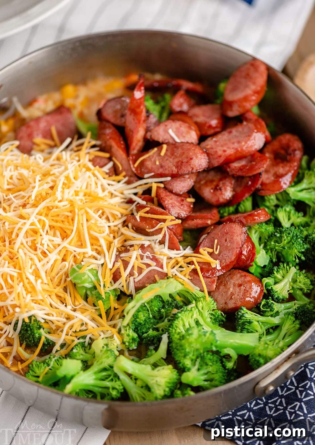 Hearty Cheesy Kielbasa and Broccoli Rice Skillet 3 Overhead view of various raw ingredients for a Kielbasa Skillet, including sliced kielbasa, chopped onions, bell peppers, and broccoli florets, ready to be combined in a pan.