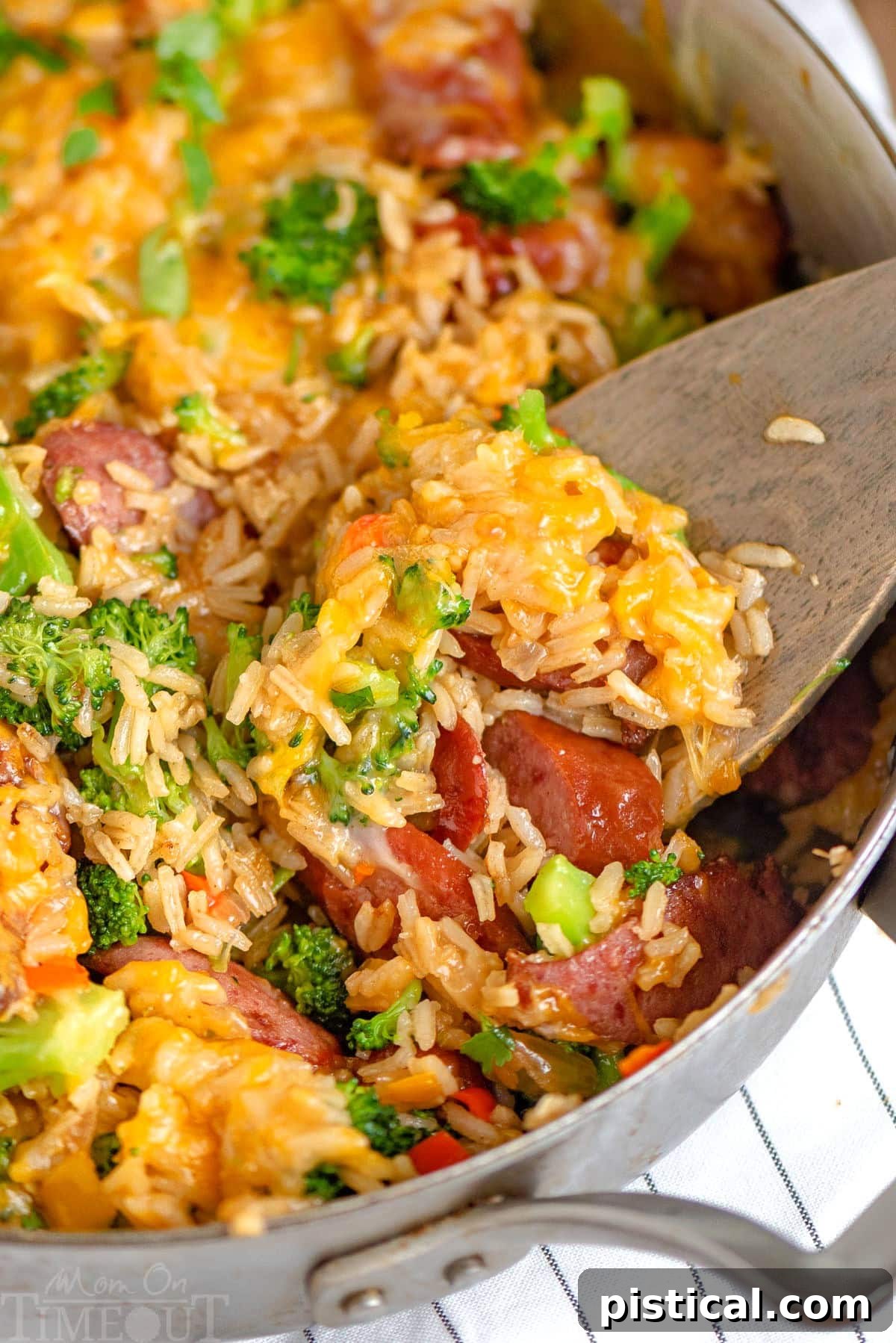 Hearty Cheesy Kielbasa and Broccoli Rice Skillet 5 A wooden spoon scooping out a generous portion of Cheesy Kielbasa Rice and Broccoli Skillet, showing off the texture and blend of ingredients.