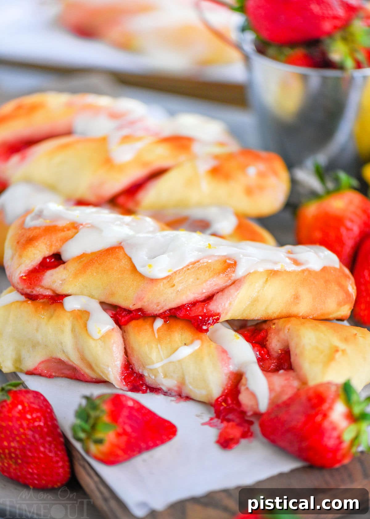 Ruby Ripple Twists 2 A beautiful side shot of golden-brown Strawberry Twists, glistening with lemon glaze, with fresh strawberries artfully arranged in front.