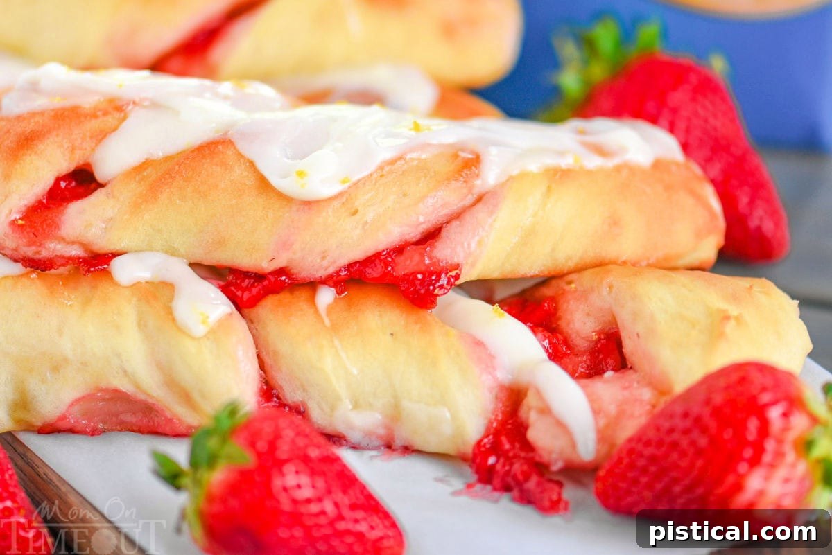 Ruby Ripple Twists 5 A delectable pile of Strawberry Twists, richly glazed, with fresh, bright red strawberries scattered beside them.