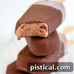 Four fudge bars that have been dipped in magic shell stacked on each other with popsicle sticks out the back.