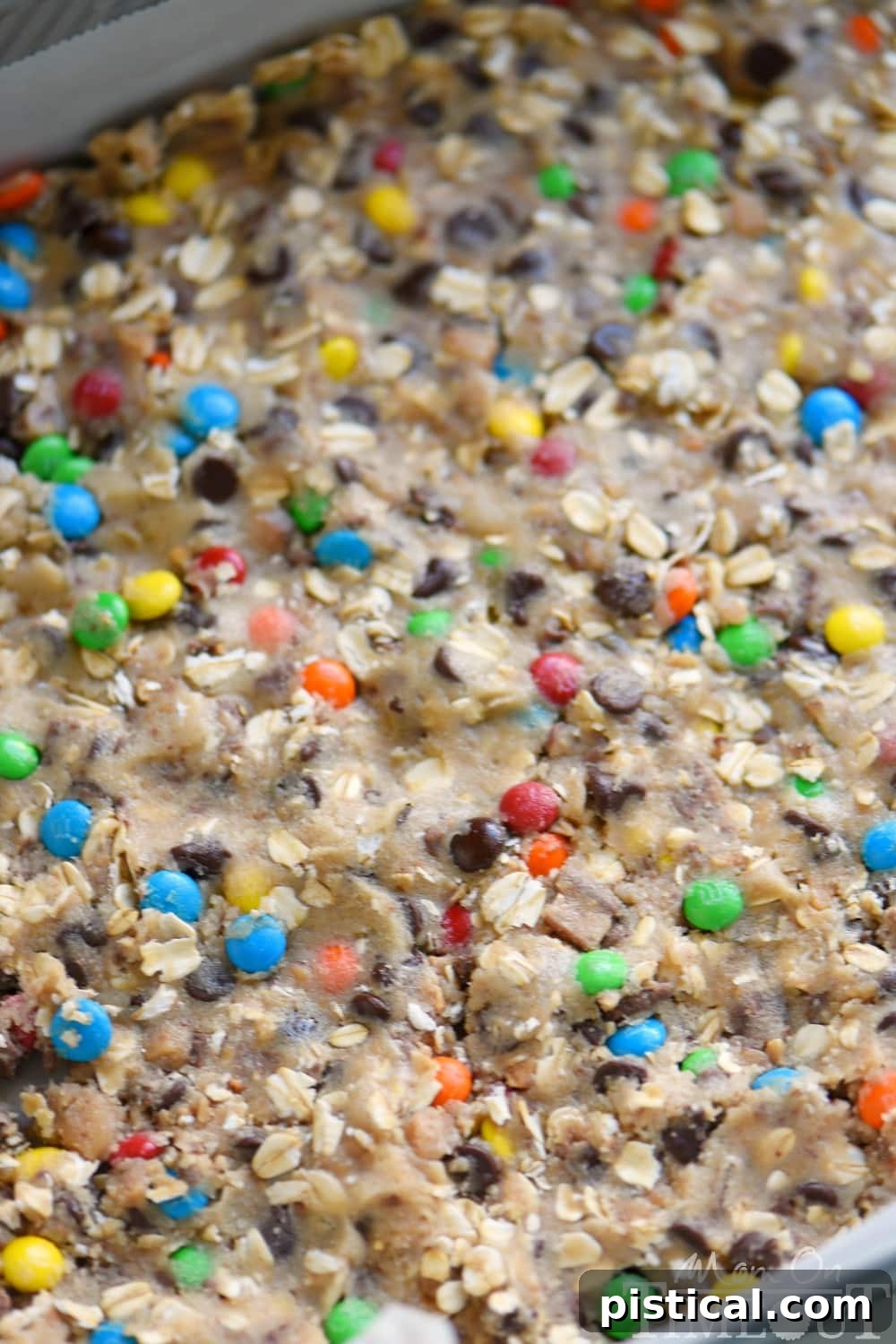 An uncut pan of Monster Fudge Bars, showcasing the cookie base, fudge layer, and colorful M&M's.