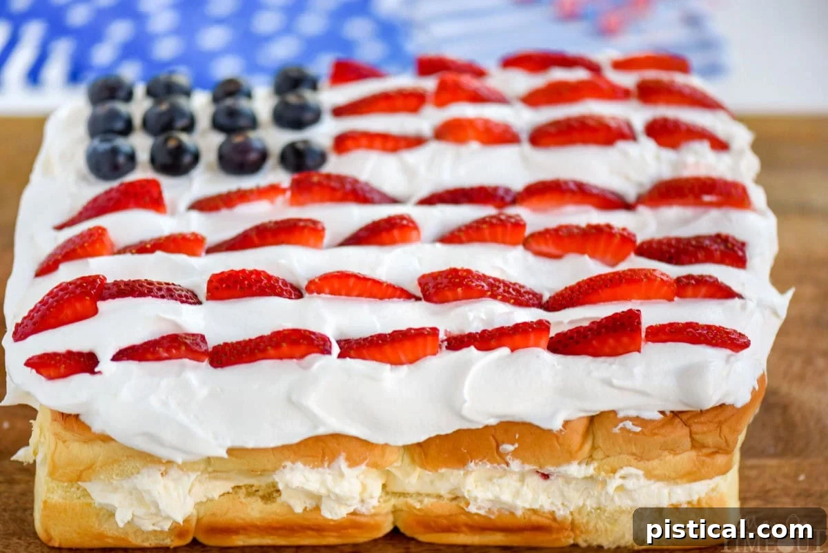 Effortless Berry Pull-Apart Cheesecake 4 Wide, front-angled view of a patriotic Hawaiian roll dessert, featuring no-bake cheesecake, strawberries, and blueberries arranged like a flag.