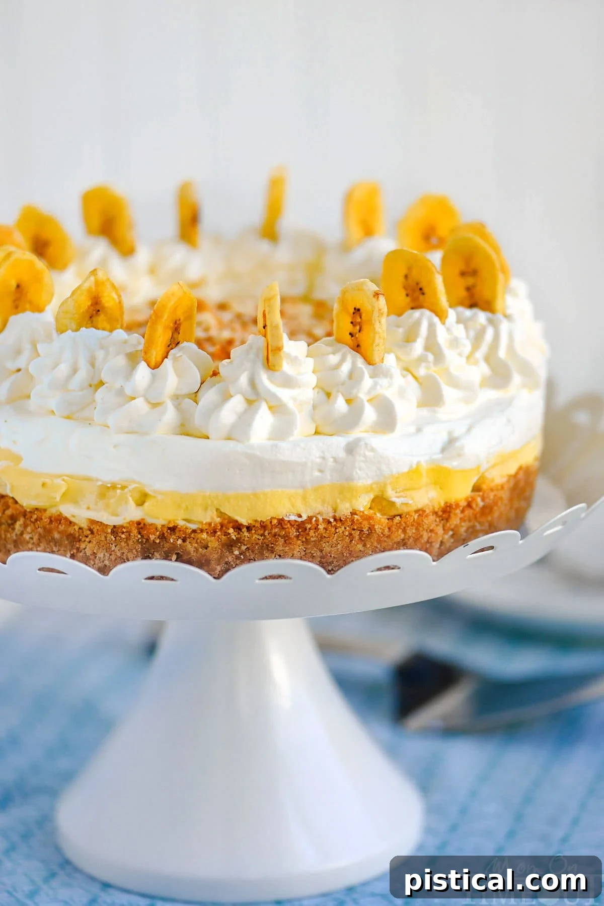 Velvet Banana Pudding Cheesecake 2 Whole no bake banana pudding cheesecake on white metal stand ready to be served.