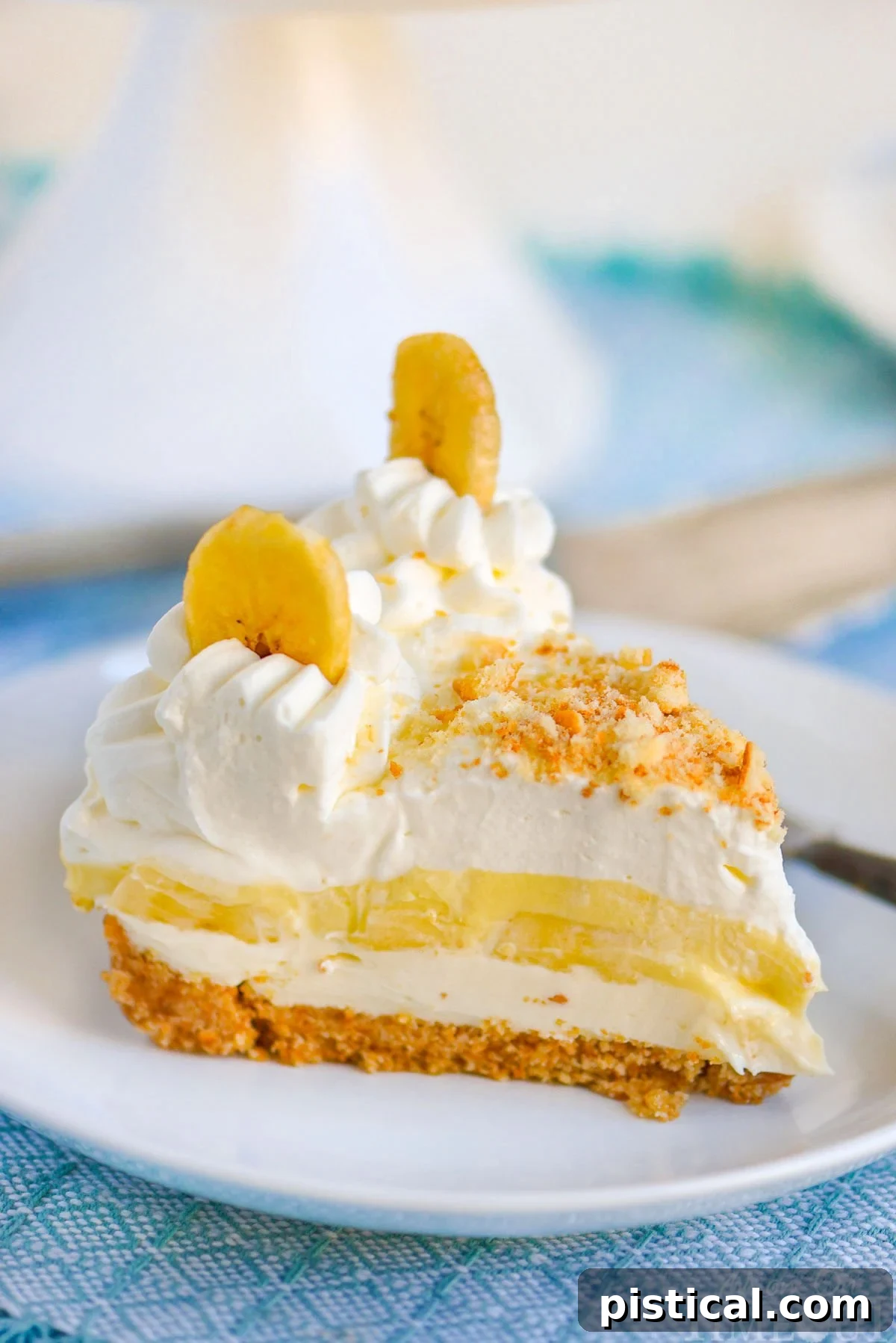 Velvet Banana Pudding Cheesecake 7 Slice of no bake banana pudding cheesecake on white round plate sitting on blue napkin.