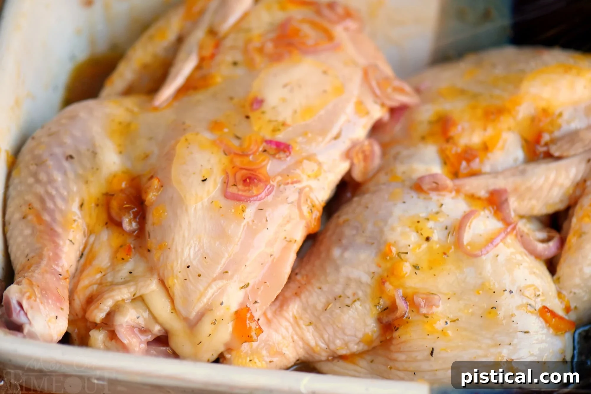 Sun-Kissed Glazed Roast Chicken 4 An uncooked chicken half soaking in the vibrant citrus marinade in a deep dish, ready for roasting.