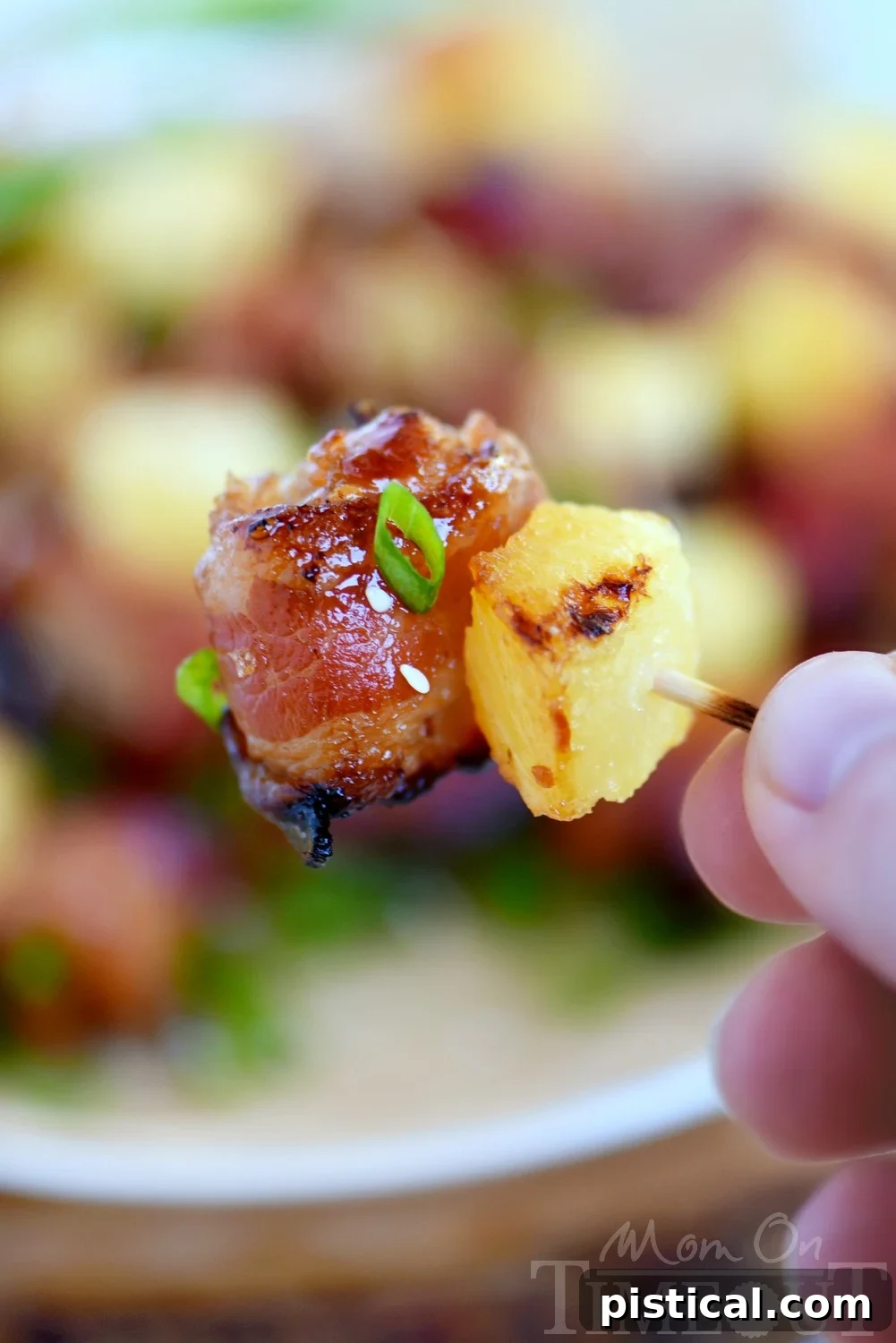 Bacon-Wrapped Teriyaki Chicken Poppers 3 Close-up of crispy Bacon Wrapped Chicken Teriyaki Bites with pineapple, garnished with green onions and sesame seeds.