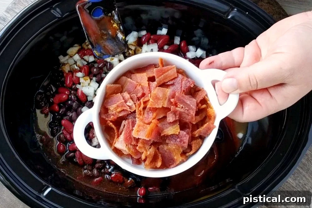 Bacon being added to the slow cooker kielbasa and barbecue beans recipe.