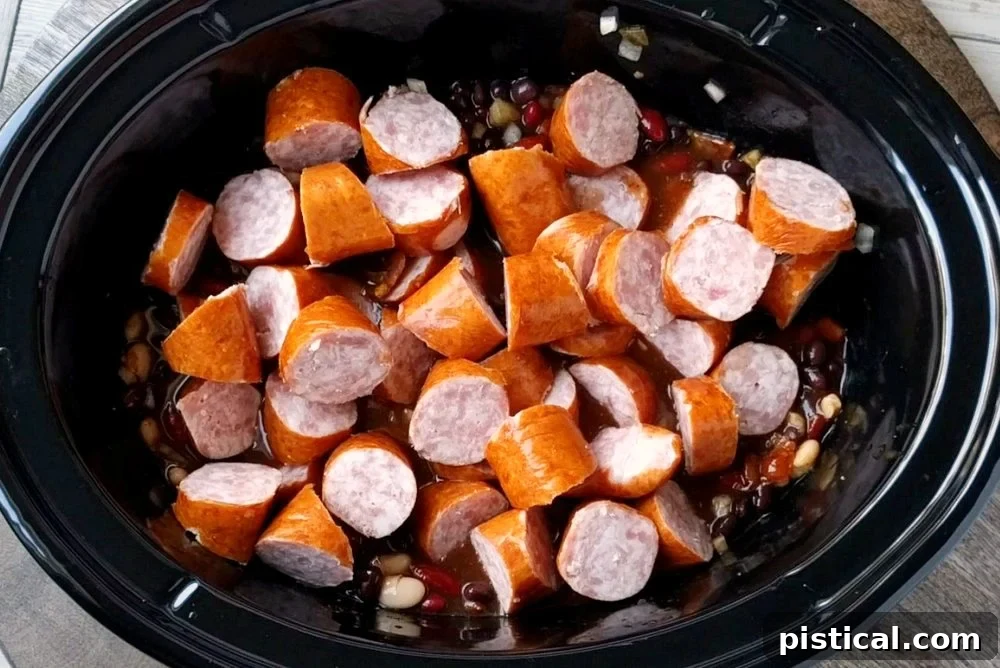 All ingredients for Slow Cooker Kielbasa and Barbecue Beans layered in the slow cooker, ready for cooking.
