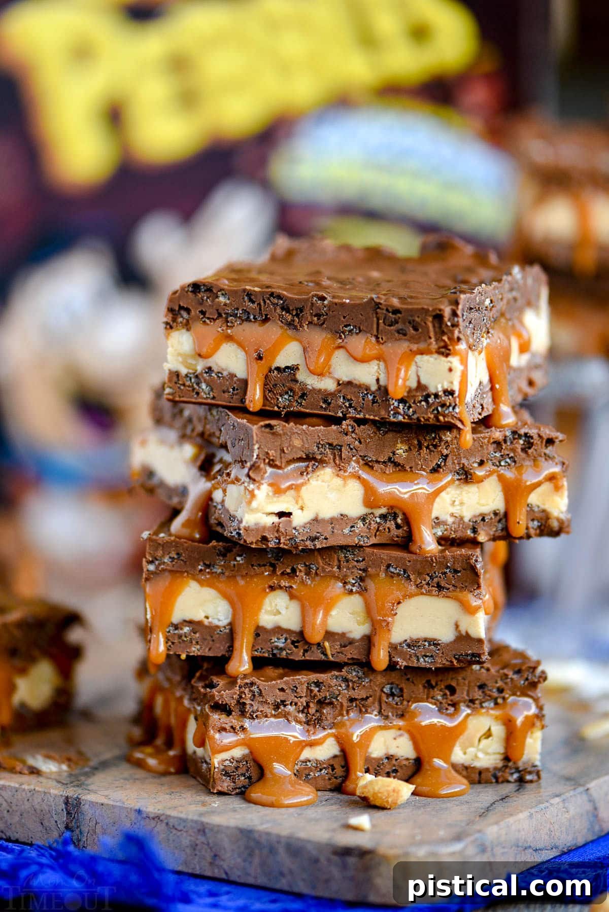 Homemade Snickers bars sit in front of a box of cereal on a brown marble cutting board, highlighting the crispy chocolate element.