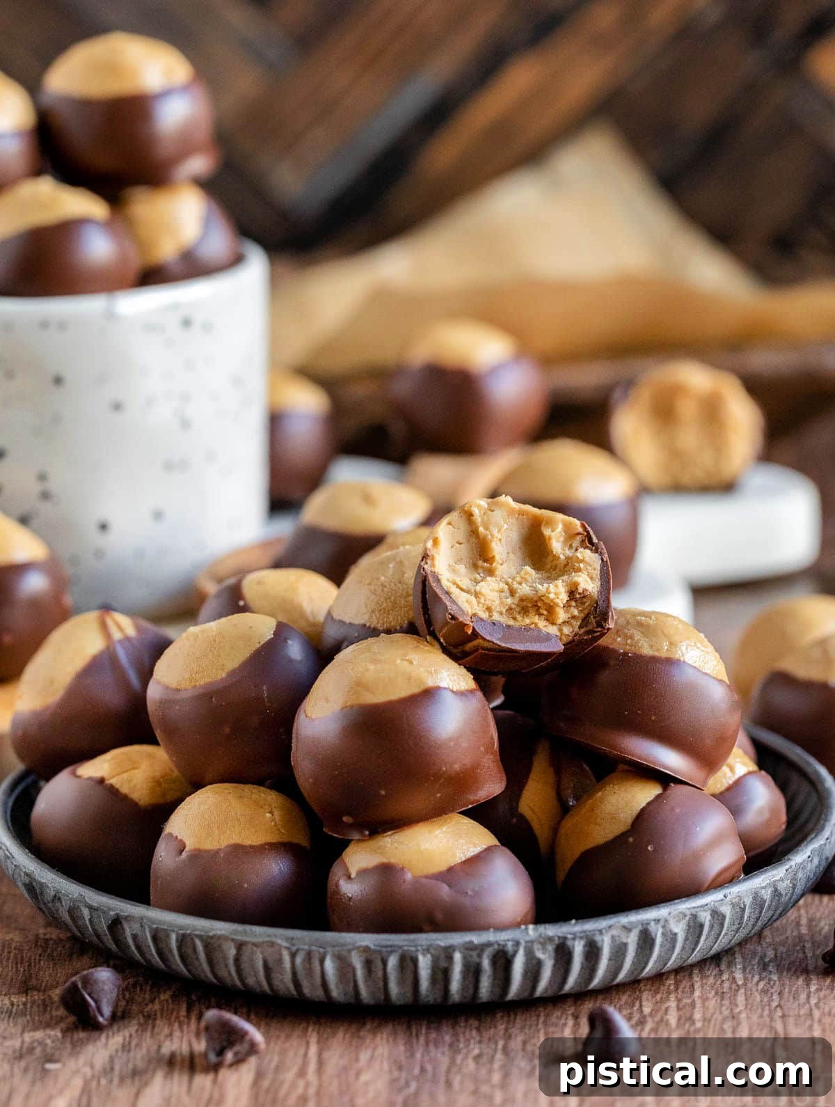 Classic Buckeyes, rich peanut butter balls half-dipped in chocolate, arranged on a silver plate with some in a white mug.