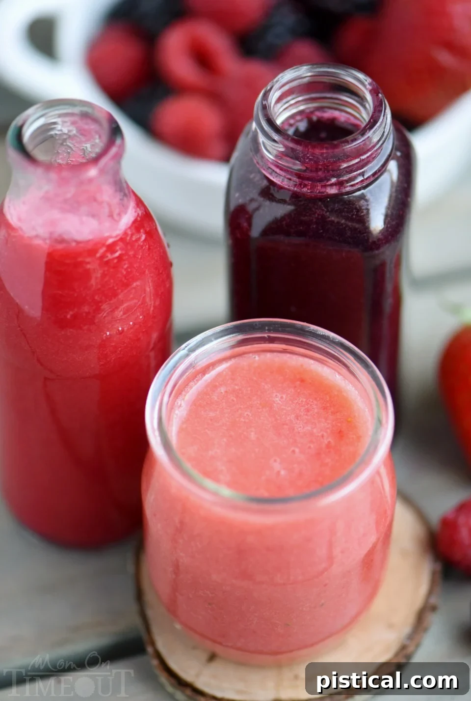 Strained berry purees in individual jars, showcasing their rich color, perfect for adding to champagne for a festive punch.