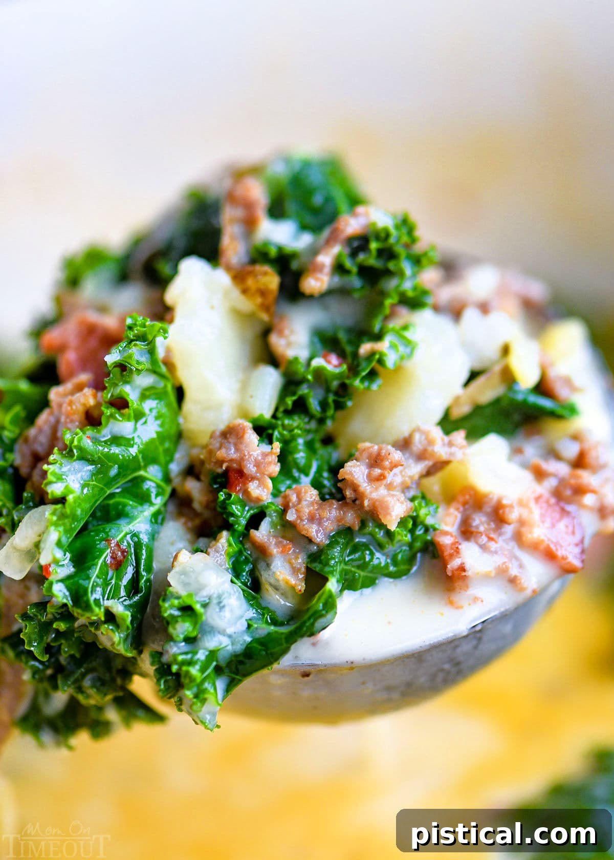 ladle full of soup made with kale, potatoes and sausage held above the pot of soup.