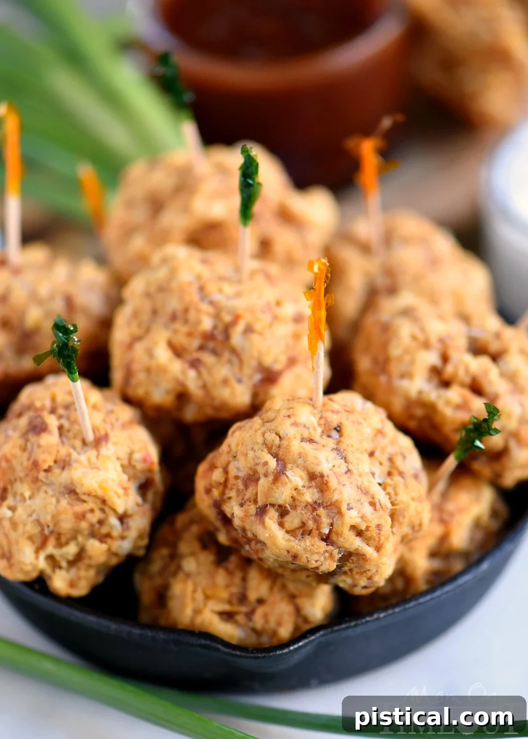 The BEST Sausage Balls are guaranteed to be a hit at your next party! So delicious, incredibly easy and perfect for game day! We like to dip them in ranch, bbq sauce, or marinara - so good! A close-up of the best homemade sausage balls with a sprinkling of fresh parsley, ready to be devoured.