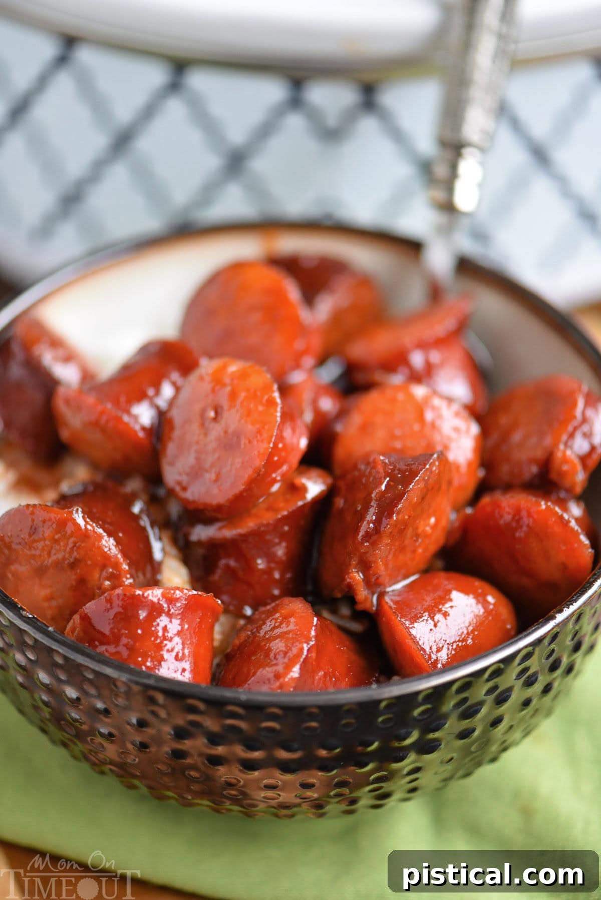 Slow cooker kielbasa bites in a bowl with rice. Slow cooker can be seen in the background.
