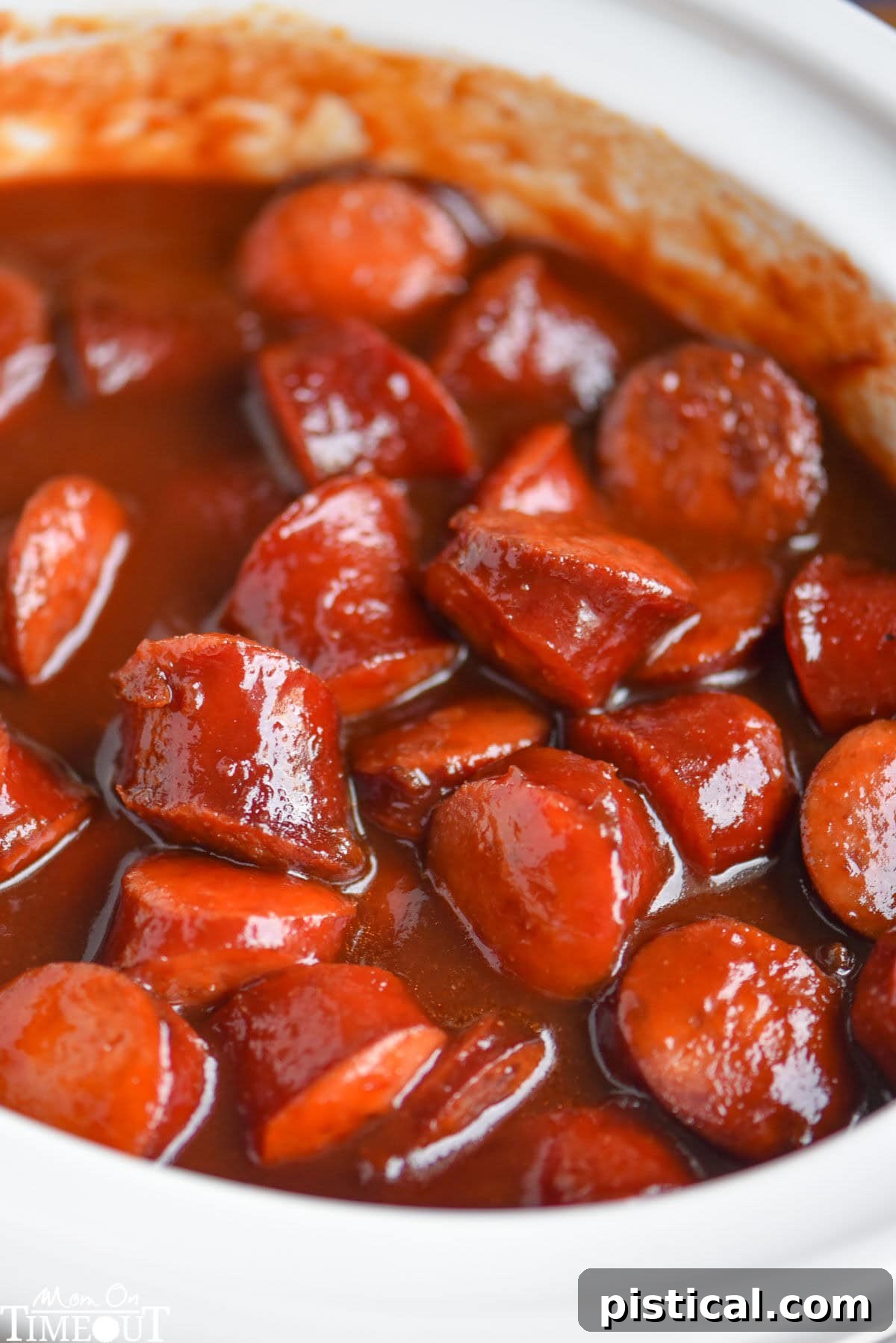 Top down look at white slow cooker full of kielbasa in a sauce made of chili sauce, bbq sauce and grape jelly.