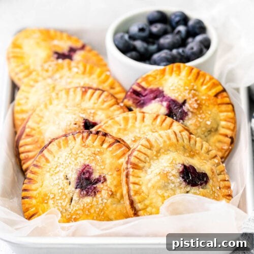Seven delicious blueberry hand pies arranged on parchment paper, filled with sweet blueberries and ready for a grab-and-go treat.