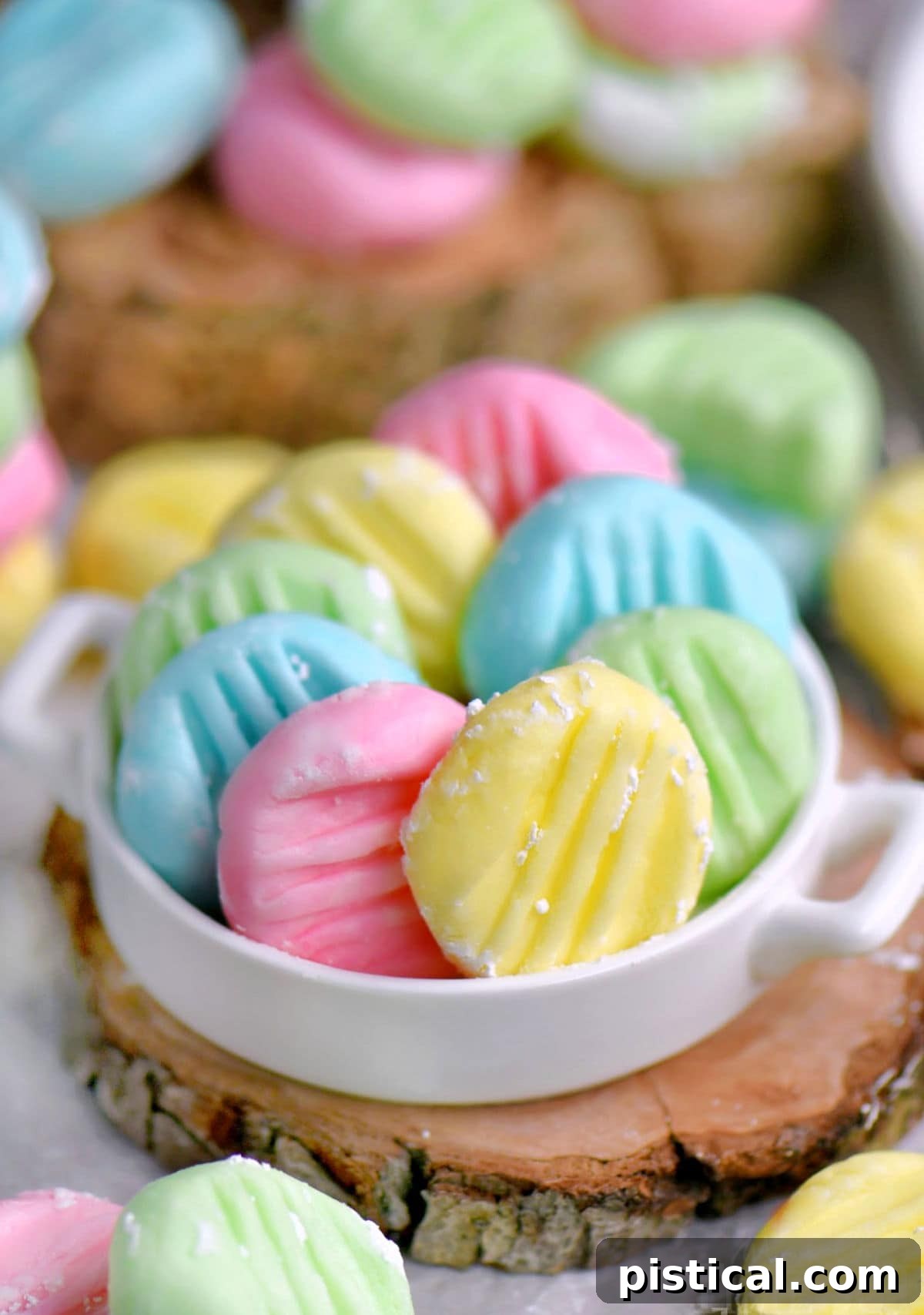 Irresistible Cream Cheese Mints 2 Colorful pastel cream cheese mints in white shallow dish sitting on wood surface.
