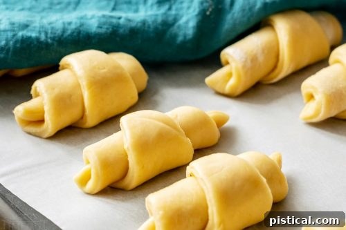 Fluffy, buttery golden crescent rolls rising on a baking sheet, ready for Easter dinner.