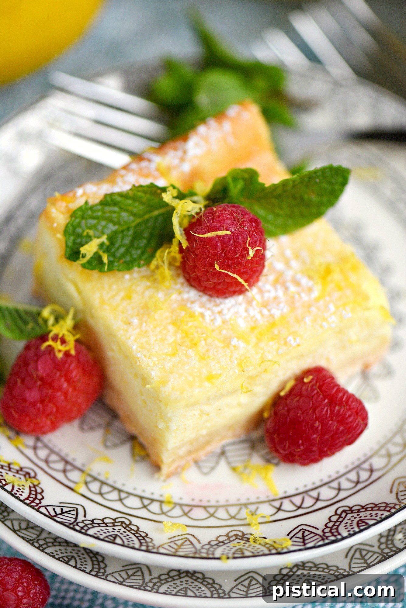 Lemon Cheesecake Bars arranged on a white serving plate, garnished with fresh raspberries and powdered sugar.