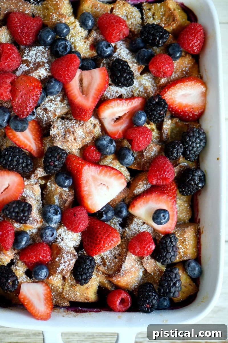 Fresh triple berries scattered on top of a ready-to-bake French toast casserole in a casserole dish.