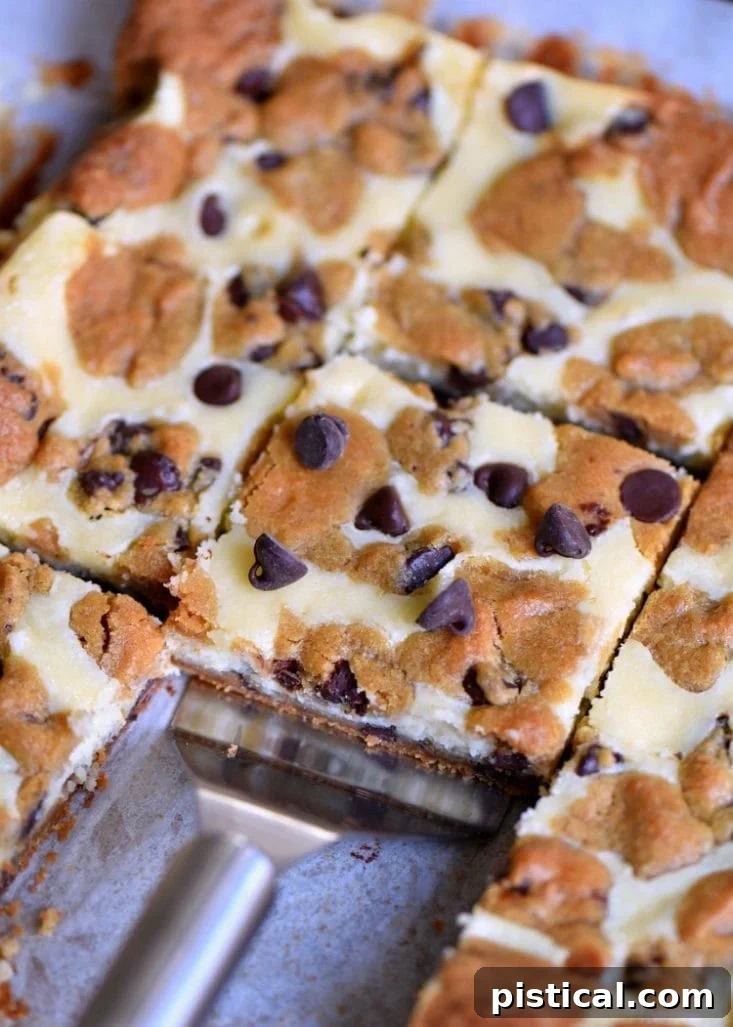 Chocolate Chip Cookie Cheesecake Bars arranged on a rustic wooden board with a serving knife.