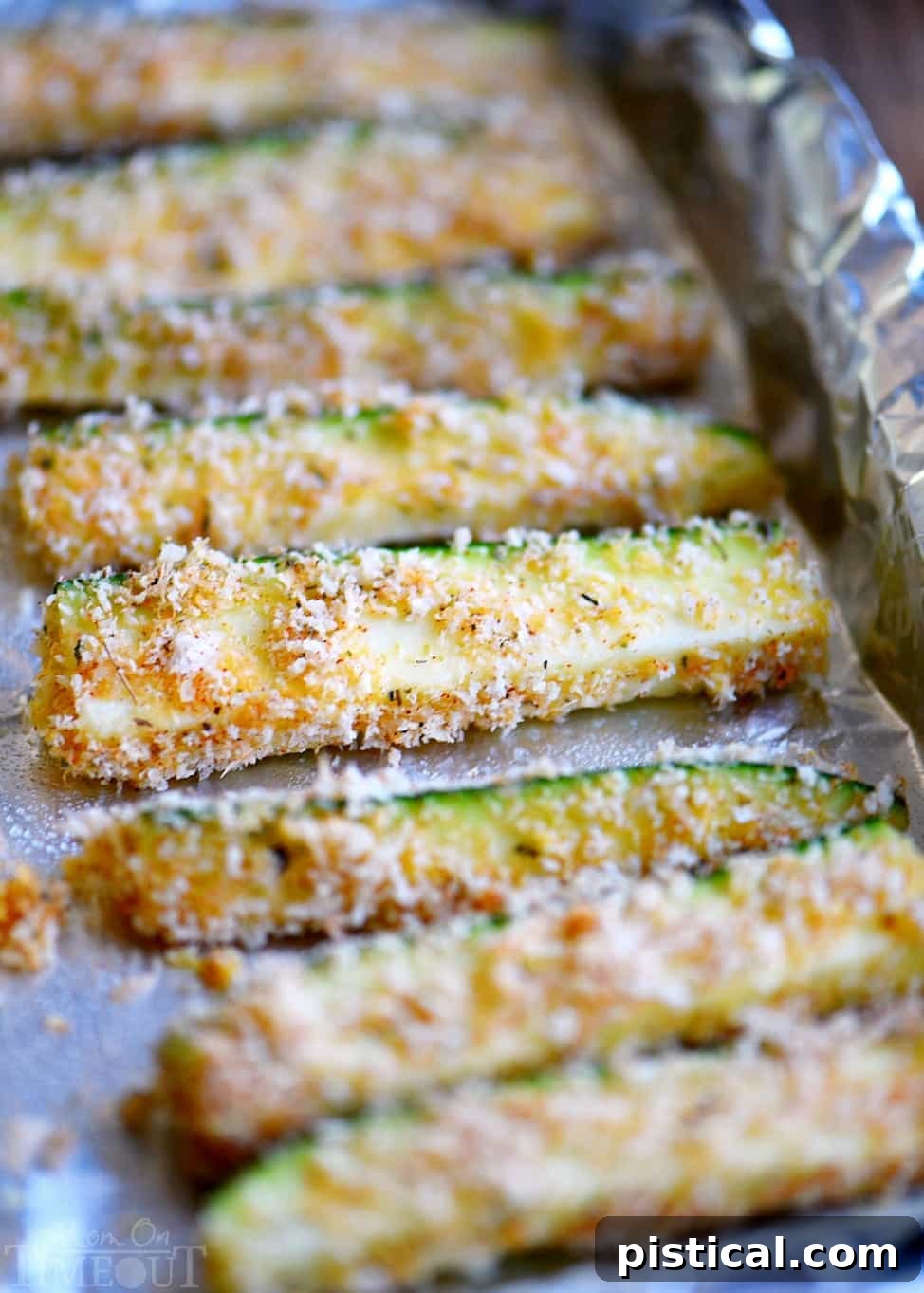 A vibrant platter of golden Baked Parmesan Zucchini Fries, garnished with fresh herbs, ready to be served.