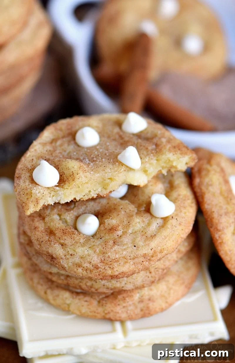 A close-up of a White Chocolate Snickerdoodle cut in half, revealing its soft, chewy interior studded with melted white chocolate chips.