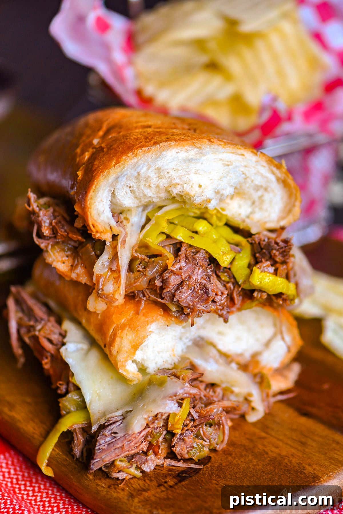 Fall-Apart Tender Slow Cooker Italian Beef Sandwiches 3 Two halves of a Italian Beef sandwich stacked on top of each other with the melted Provolone cheese and pepperoncinis showing.