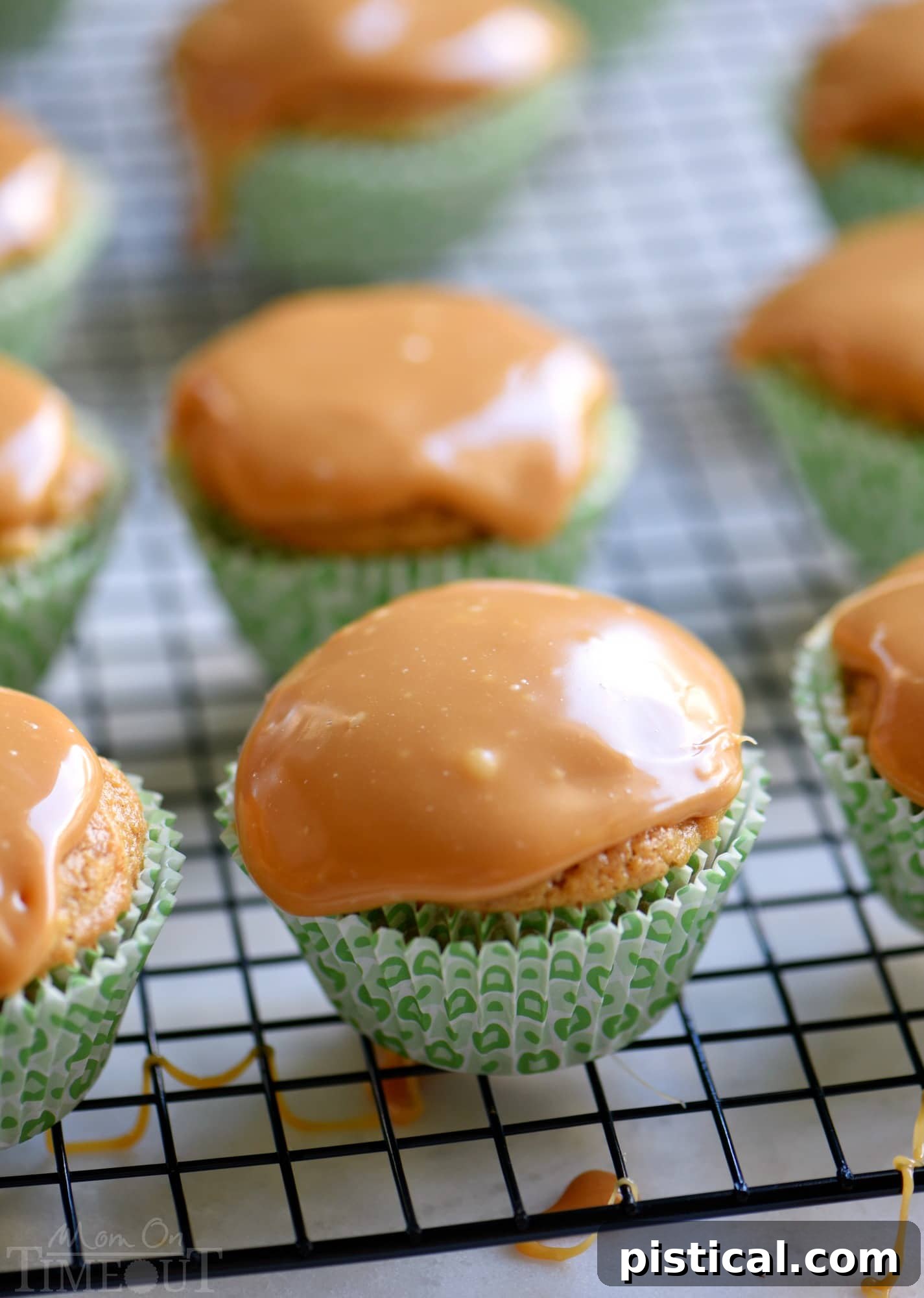 A stunning close-up of a caramel apple cupcake, showcasing its perfectly baked texture and the rich, glossy caramel frosting. It’s presented on a rustic wooden coaster, hinting at the warm, cozy feel of autumn.