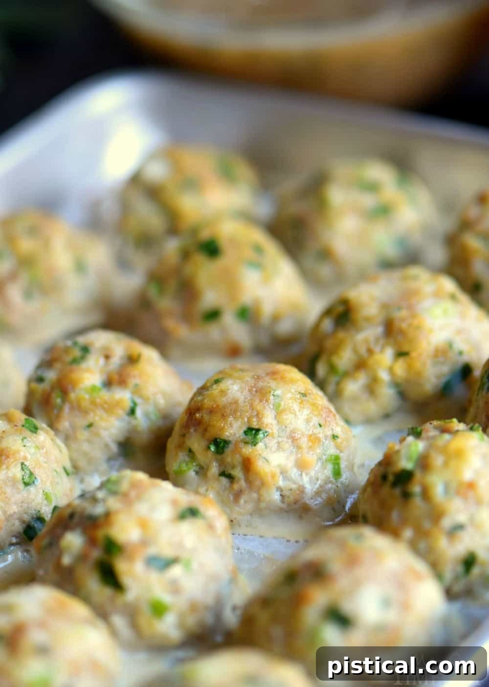 Close-up of perfectly baked turkey meatballs resting on a baking sheet, ready for gravy.