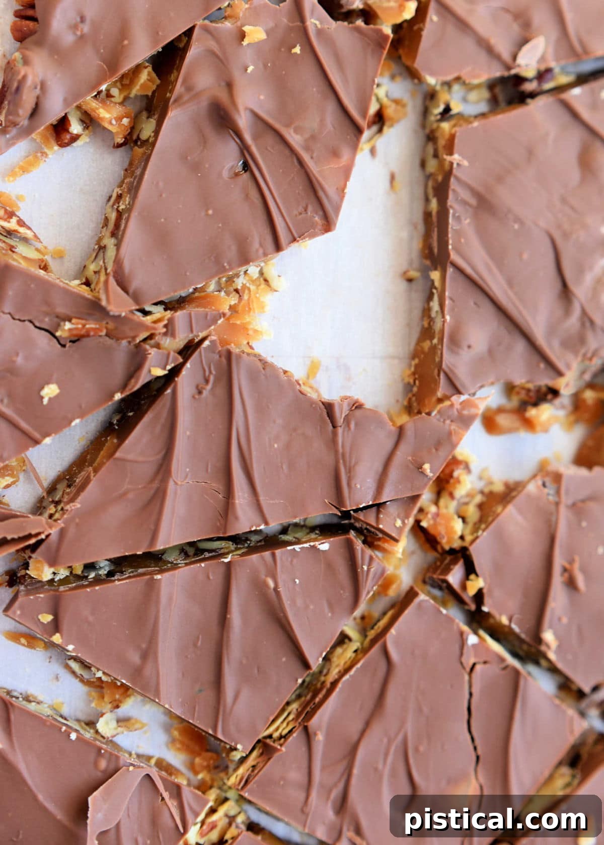 toffee candy broken up on a piece of parchment paper into smaller pieces.