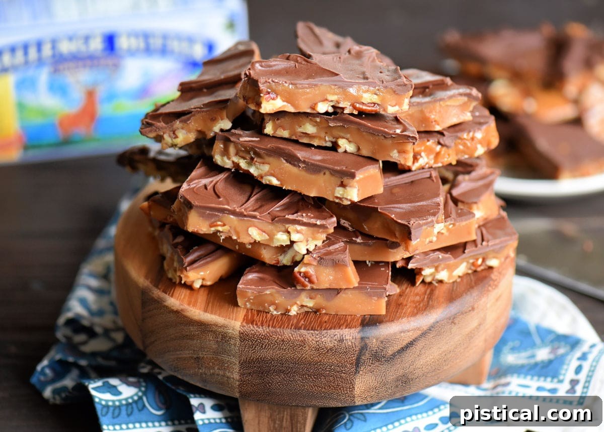 toffee piled high on dark wood round board sitting on blue and white background. box of butter in background.