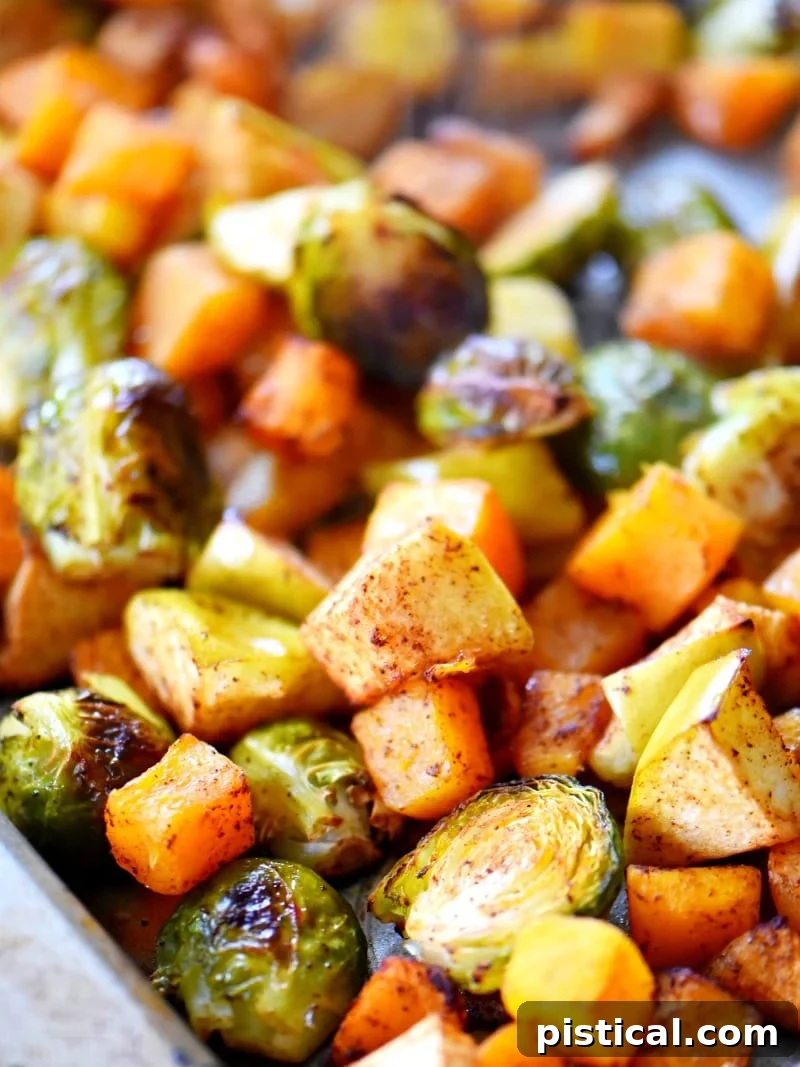 Oven roasted Brussels sprouts, butternut squash, and apples spread on a baking sheet, ready to serve
