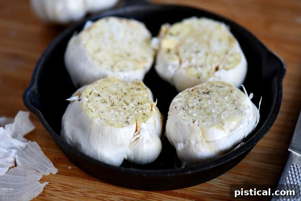 Whole garlic heads with the top quarter sliced off, ready for roasting.