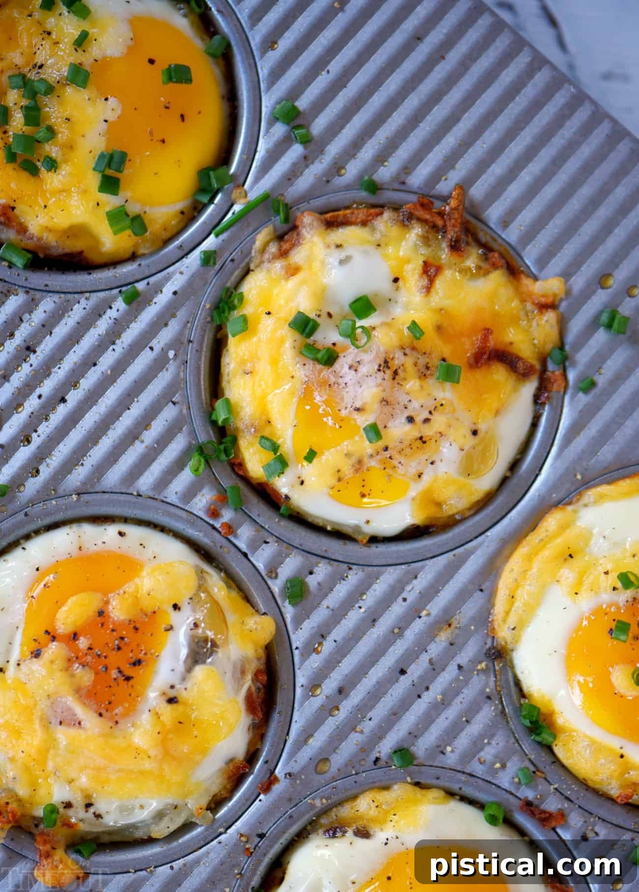 Tray of freshly baked Sausage and Egg Hash Brown Cups, garnished with chives, ready to be served.