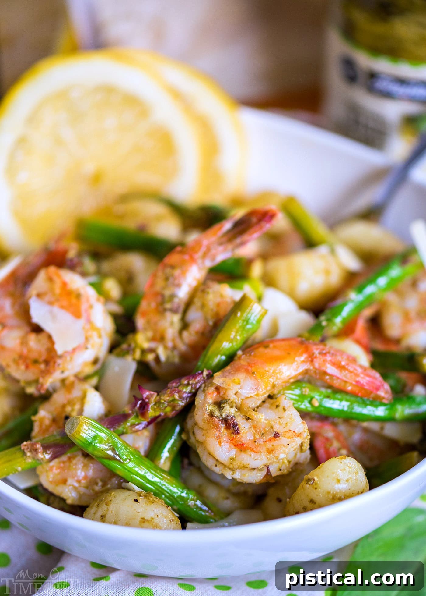 Plated Pesto Shrimp Gnocchi with Asparagus, garnished with Parmesan.