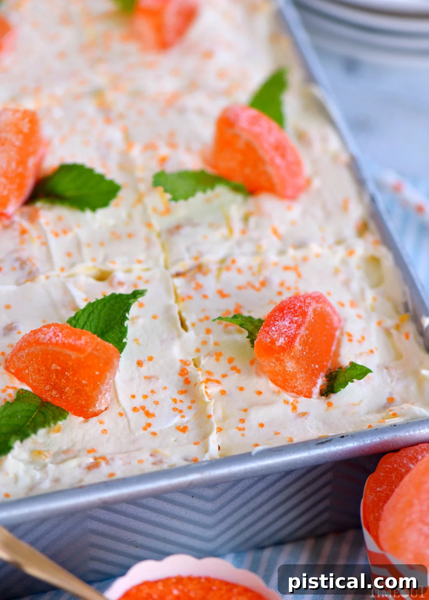 A whole Orange Creamsicle Poke Cake in a 9x13 inch metal baking dish, beautifully garnished with candied orange slices and fresh mint leaves, ready to be served.